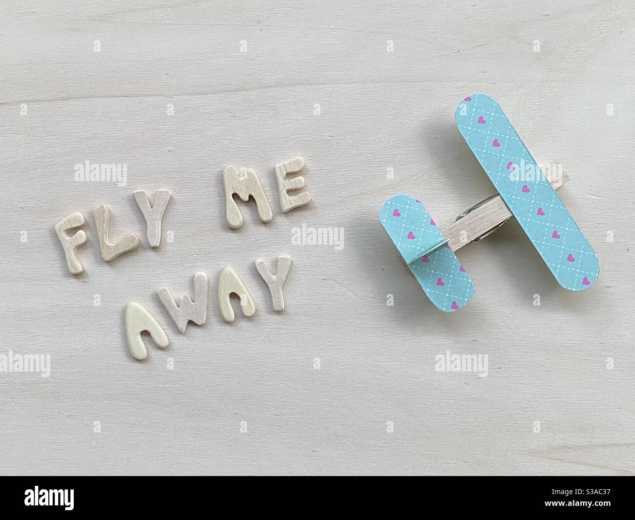 Fly me away, kreativer Text mit Holzbuchstaben und einer hölzernen Wäscheklammer Flugzeug komponiert Stockfoto