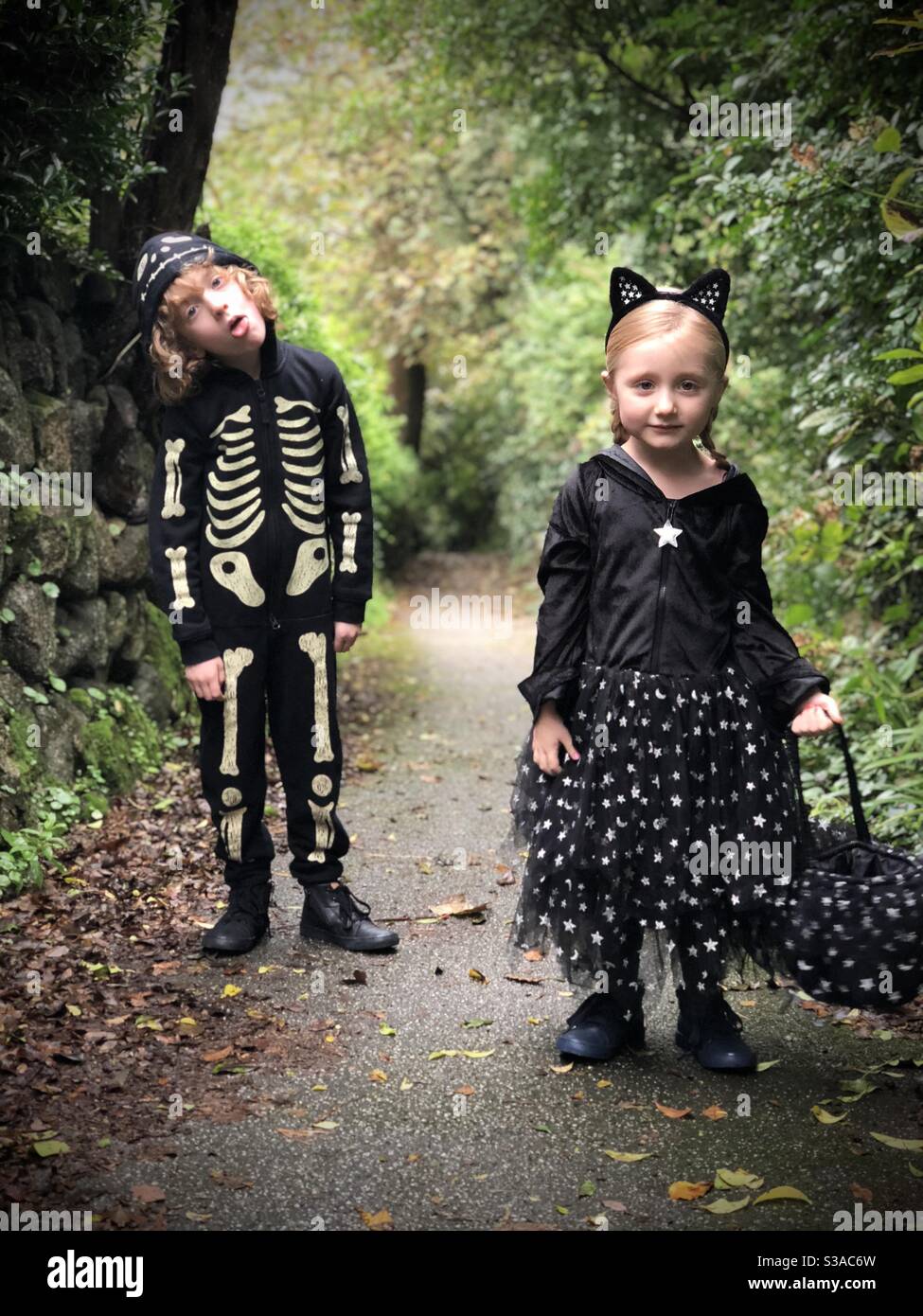 Zwei Kinder in Halloween-Kostümkleid auf Fußpfad aus Trick oder Treating. Stockfoto