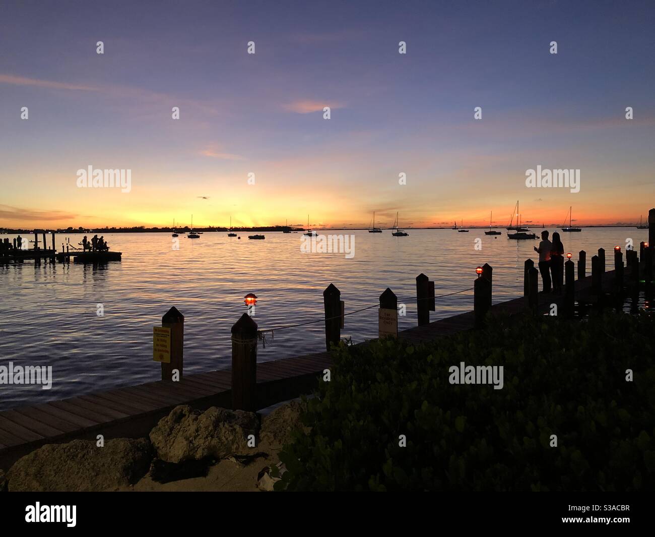 Sonnenuntergang über der Bucht mit einem Paar in Silhouette an einem Pier in Key Largo, Florida USA. - Smartphone-aufgenommenes Stockfoto