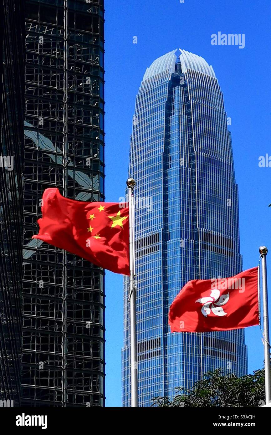 Die Flaggen von Chiba und Hong Kong mit dem IFC Turm im Hintergrund. - Smartphone-aufgenommenes Stockfoto