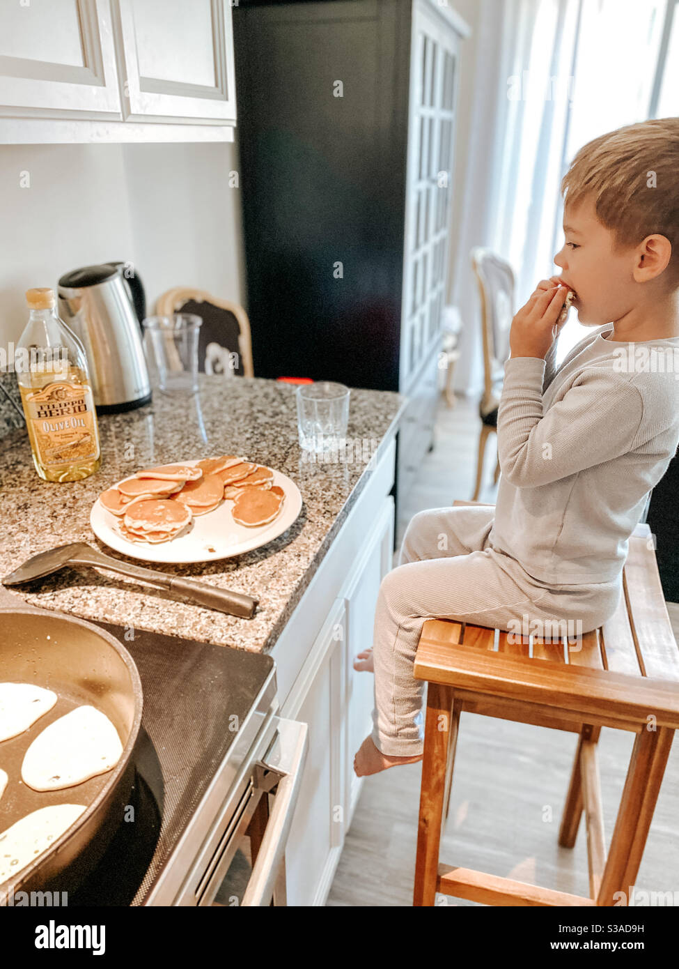 Junge in der Küche essen Pfannkuchen Stockfoto