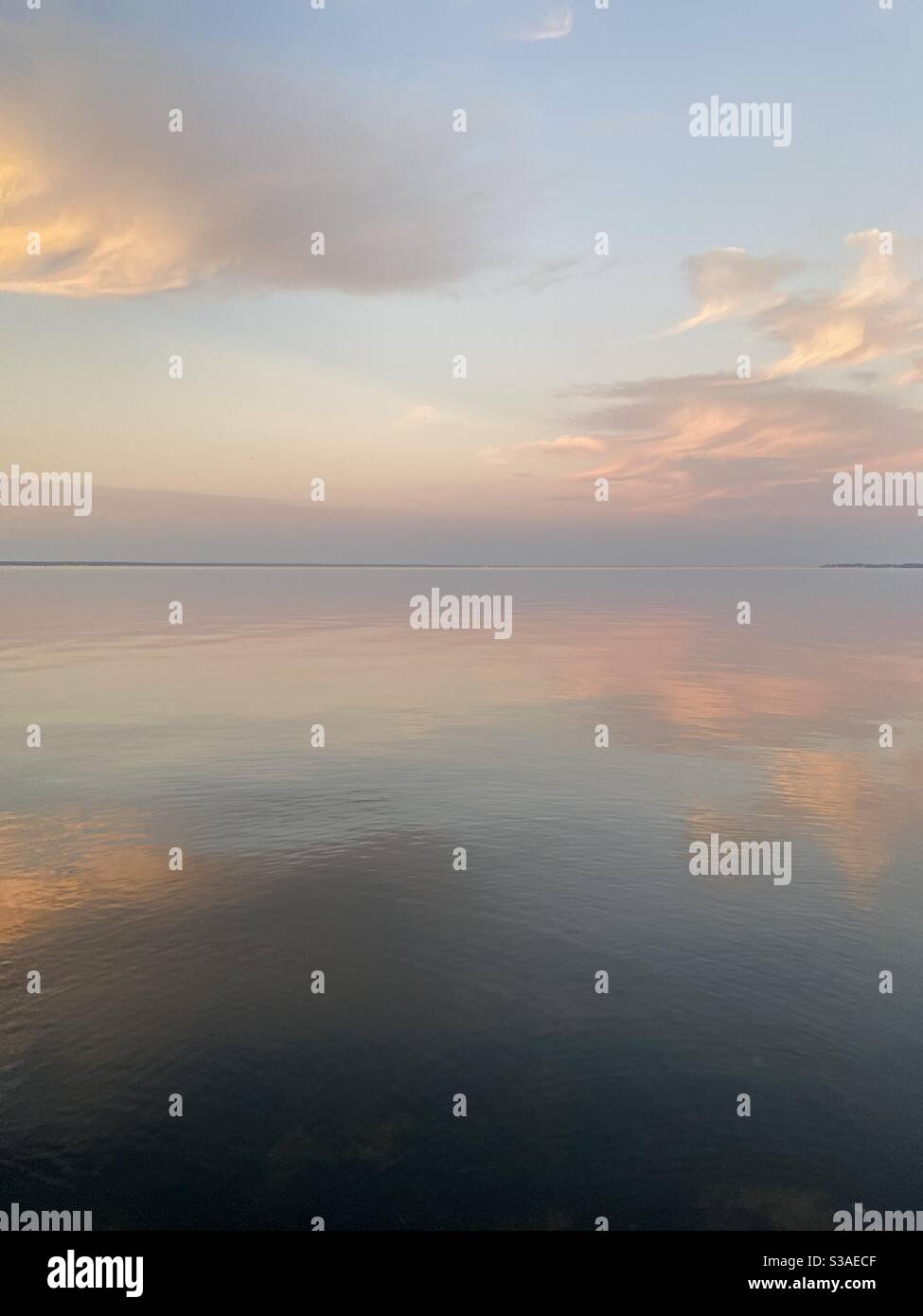 Sanfter, pastellfarbener Sonnenuntergang am ruhigen, noch in der Bucht abgehenden Wasser Stockfoto