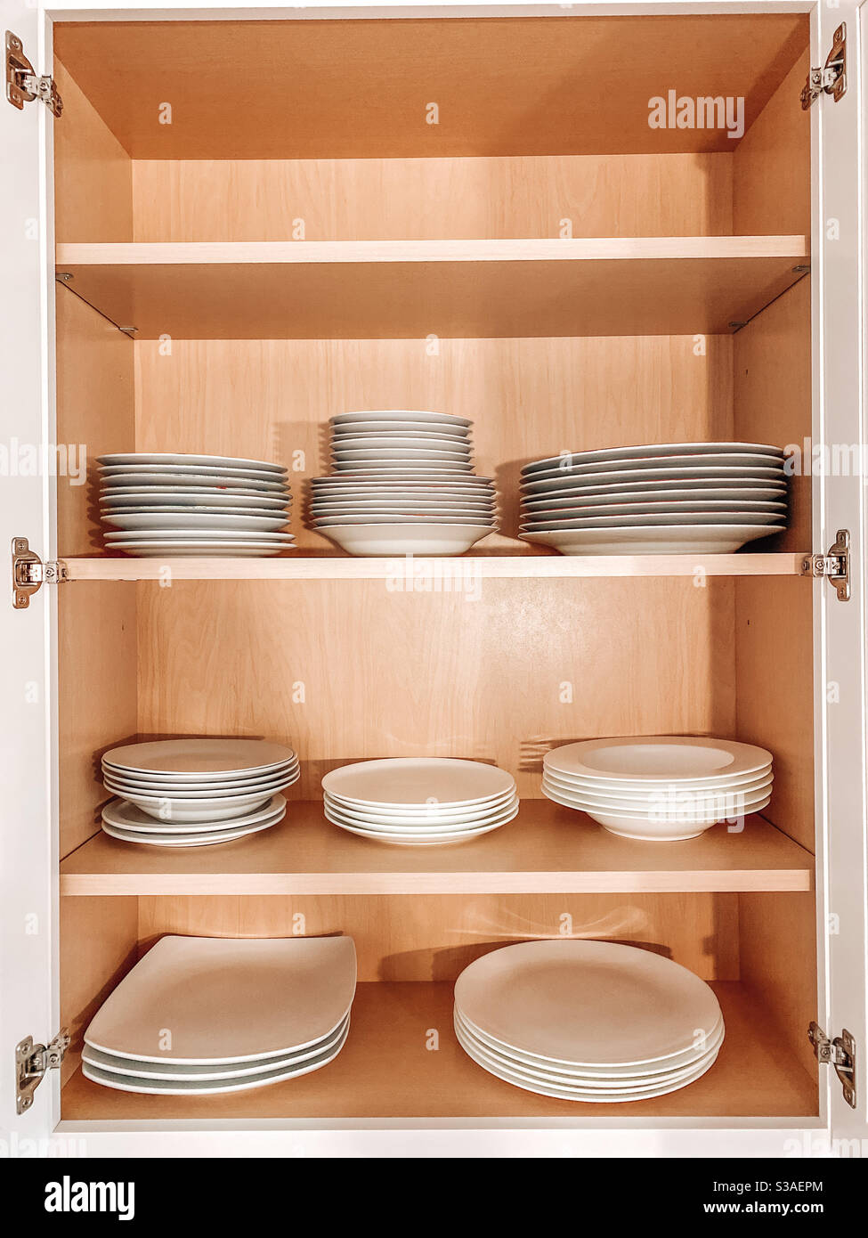 Minimalistischer und organisierter Holzschrank gefüllt mit weißen Tellern und Schüsseln Stockfoto
