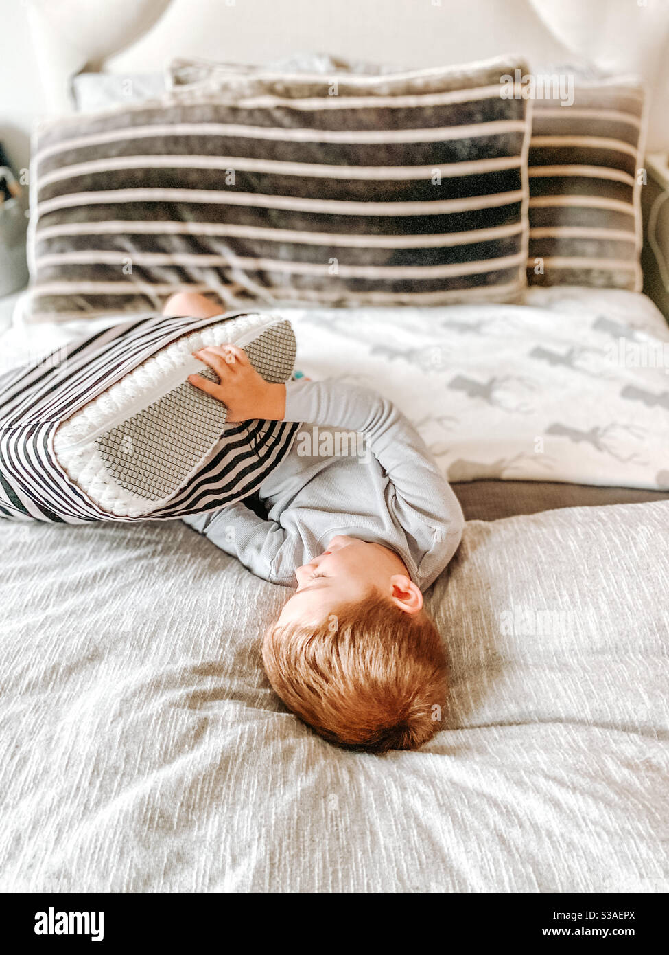 Junge spielt mit einem Kissen auf einem Bett Stockfoto