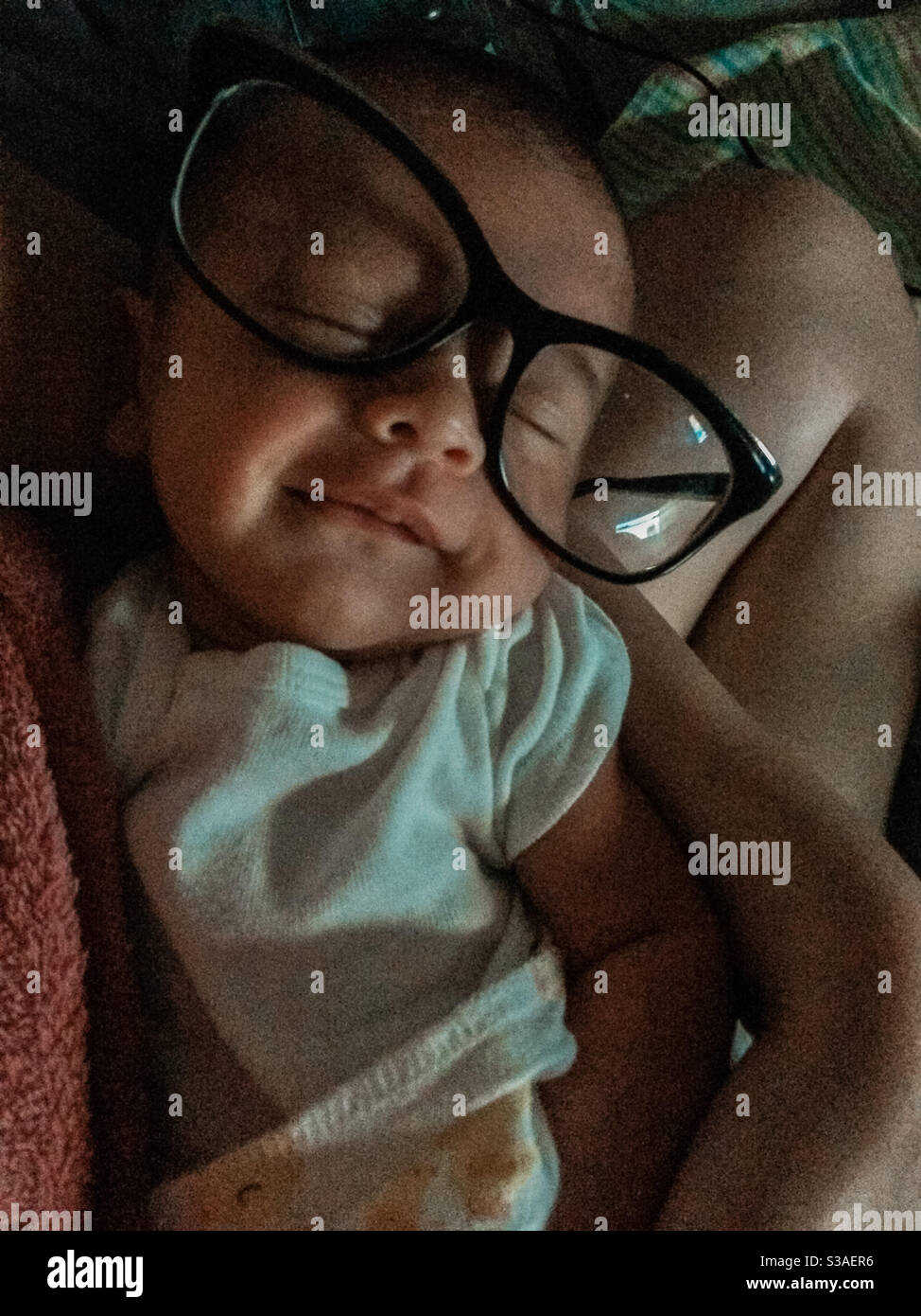 Kleines kleines Baby, das mit riesigen Gläsern schläft und lächelt Stockfoto