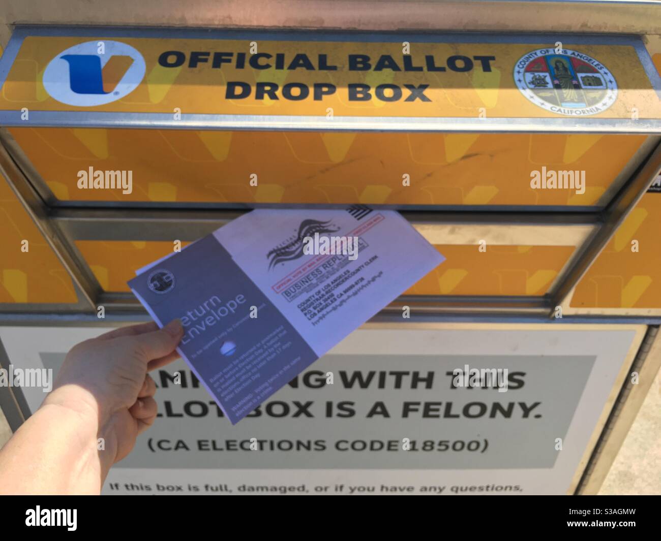 Eine Hand, die bei der Wahl im November 2020 einen Briefwahlzettel in eine offizielle Los Angeles County-Wahlurne abgibt. Stockfoto
