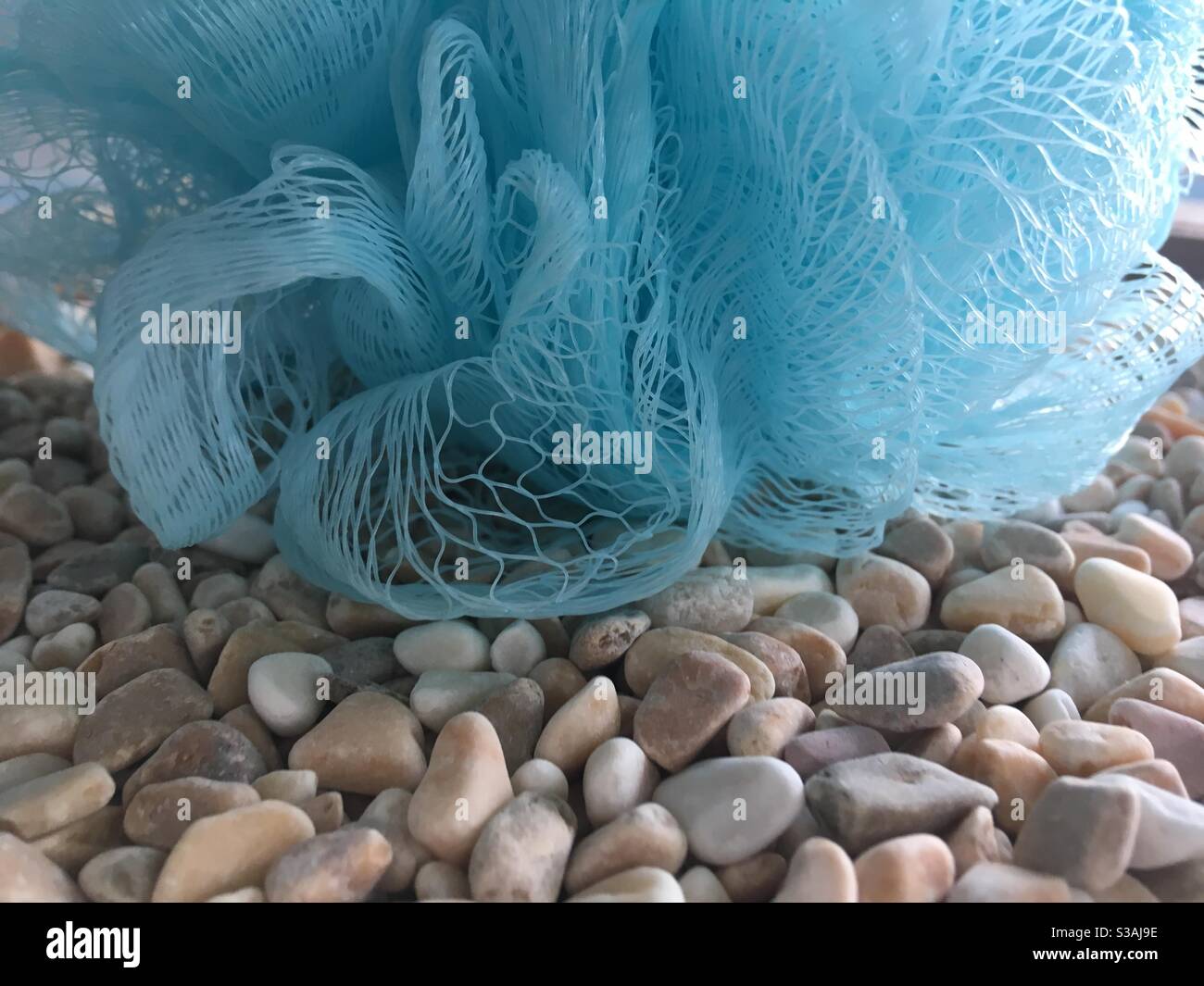 Blauer Waschschwamm auf naturfarbenen Steinmellen - Smartphone-aufgenommenes Stockfoto