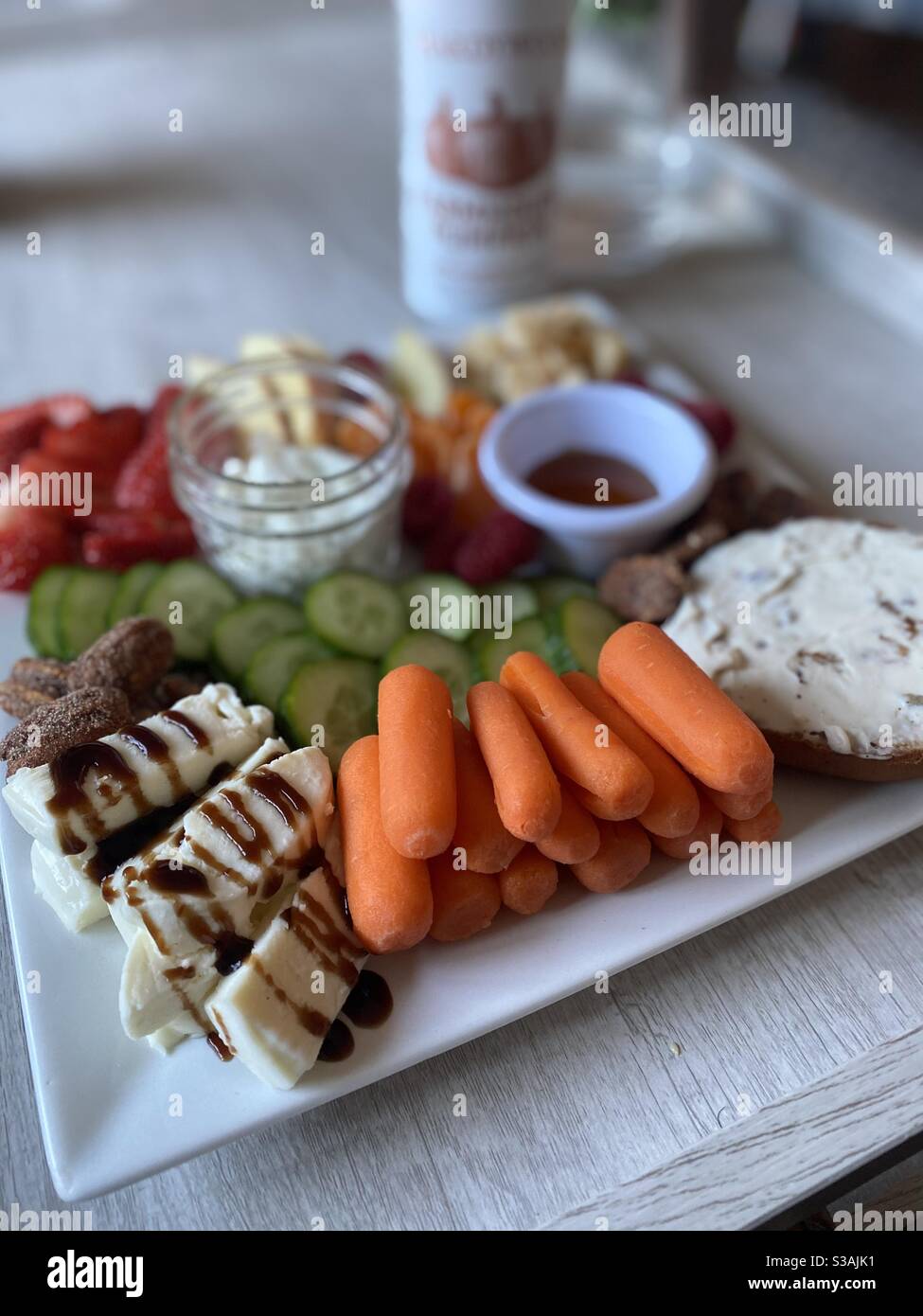 Gesunde Snack-Tablett mit frischem Obst, Gemüse, Käse, Honig, kandierten Nüssen und Gurken Joghurt Dip Stockfoto