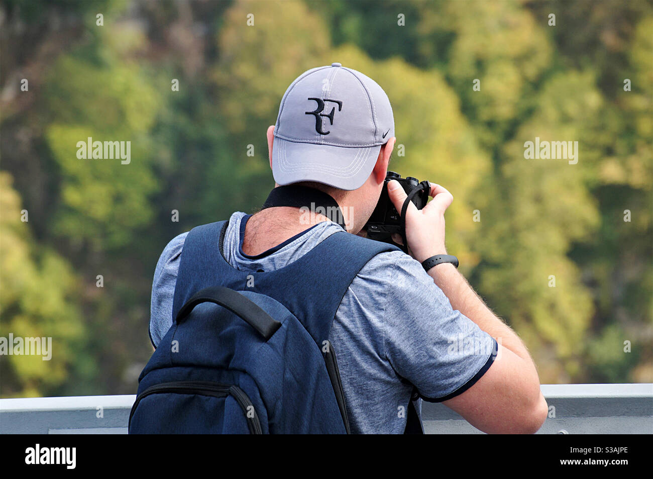 Der junge Mann in einer Mütze fotografiert mit der Kamera - Smartphone-aufgenommenes Stockfoto