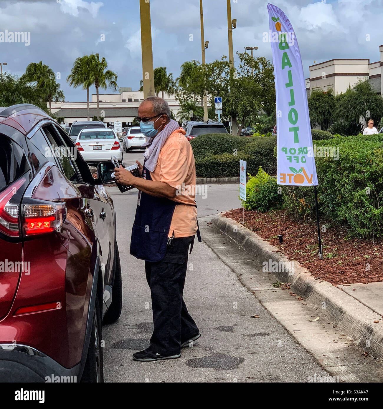Ein Umfragearbeiter verwendet Zangen, um einen Briefwahlzettel von einem Autofenster für die berührungslose Absetzung früher Abstimmung in Orlando, Florida, anzunehmen Stockfoto