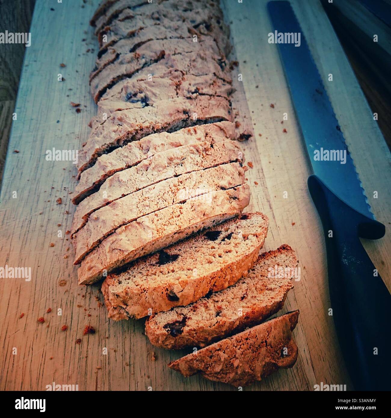 Ein Foto von Biscotti auf einem Schneidebrett mit einem Messer, bereit, zurück in den Ofen zu gehen, nachdem sie geschnitten - Smartphone-aufgenommenes Stockfoto