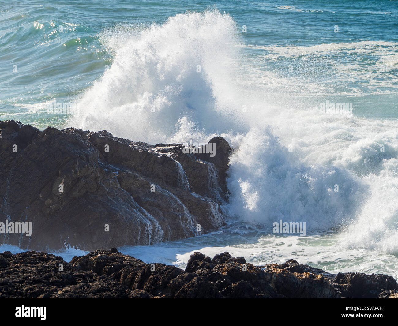 Eine Explosion von weißem Wasser als Wellen auf Felsen stürzen Stockfoto