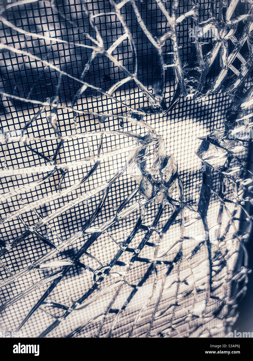 Zerschmettert! Zerrissenes Glas mit einem Loch, das aus einem Stein gebrochen ist, silbergrau, Fliegenschutz dahinter, Muster - Smartphone-aufgenommenes Stockfoto