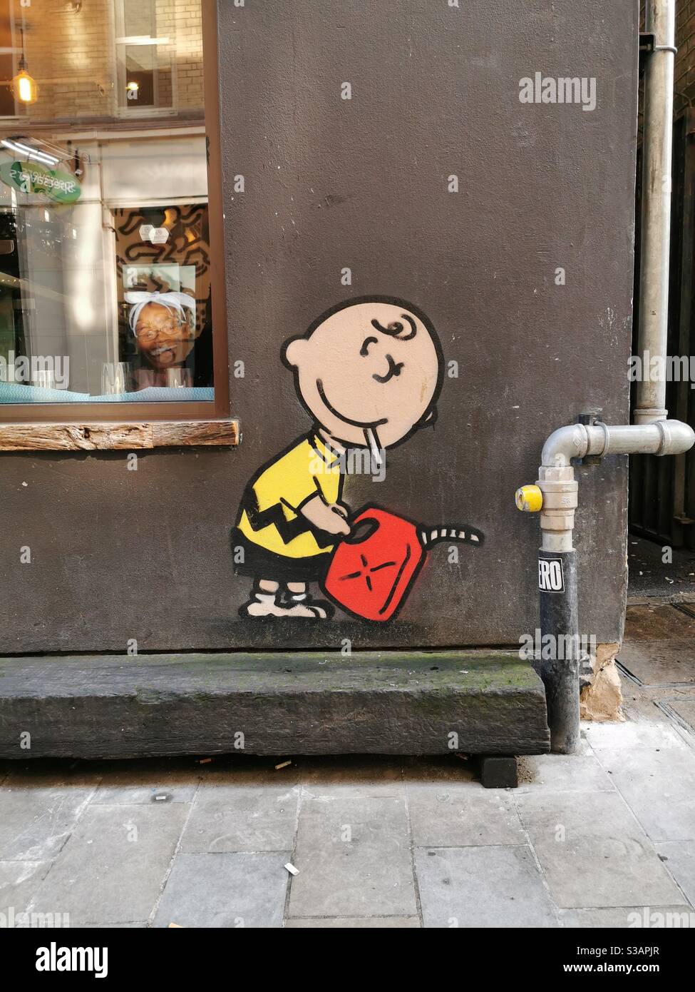 Charlie Brown raucht eine Zigarette mit Benzinkanister, Street Art Graffiti London Stockfoto