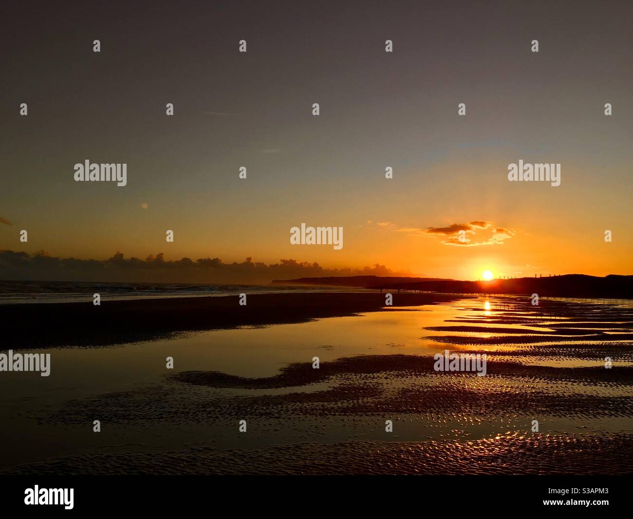 Sonnenuntergang an einem nassen Strand Stockfoto