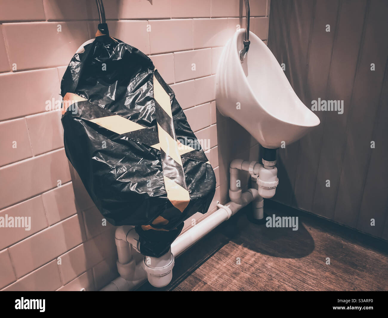 Ein Urinal wird in den öffentlichen Toiletten eines Mannes als Folge der sozialen Distanzierungsrichtlinien abgesperrt, um die Ausbreitung des Coronavirus zu verhindern. Stockfoto