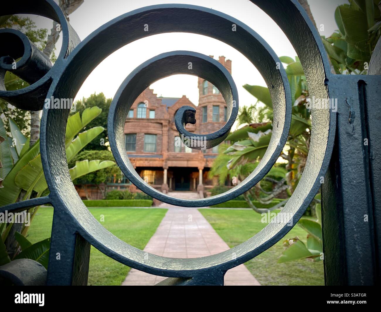 LOS ANGELES, CA, JUL 2020: Blick durch eine schmiedeeiserne Spirale im Tor des historischen Stimson House, einem richardsonischen romanischen Herrenhaus aus dem Jahr 1891, im Stadtteil University Park. - Smartphone-aufgenommenes Stockfoto