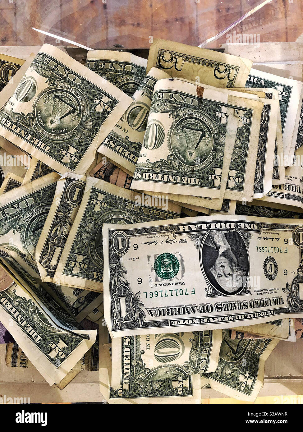 Haufen Geld in Tip-Glas oder Box, um Tipps zu sammeln. US-Dollar-Geldscheine Stockfoto