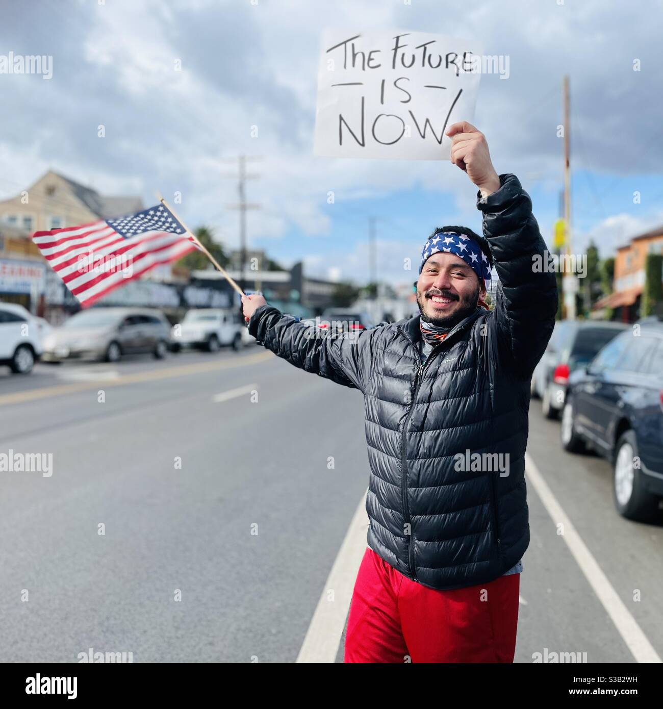 Mann mit amerikanischer Flagge und einem Schild feiert Joe Biden zum Präsidenten der Vereinigten Staaten gewählt. Stockfoto