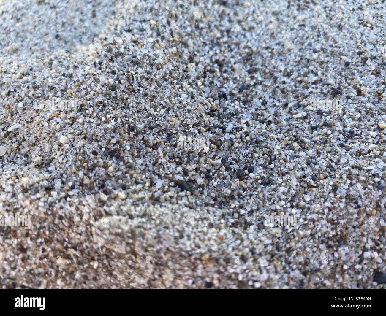 Makroansicht von Sandkörnern an einem Strand mit flachem Fokus Im Schatten - Smartphone-aufgenommenes Stockfoto