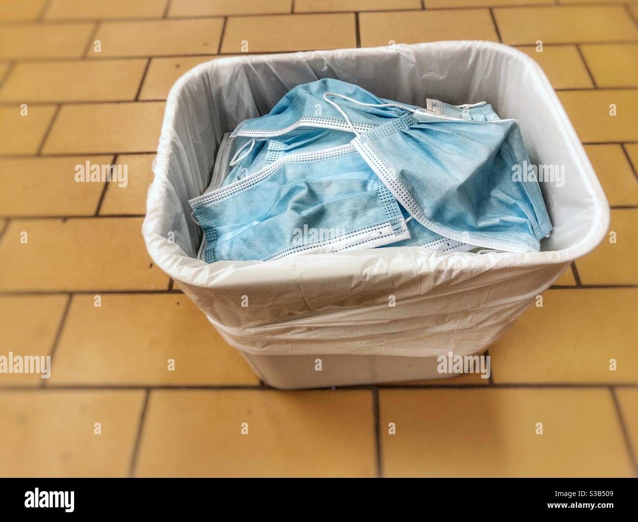 Ein Papierkorb voller weggeworfener Einweg-Gesichtsmasken. Stockfoto