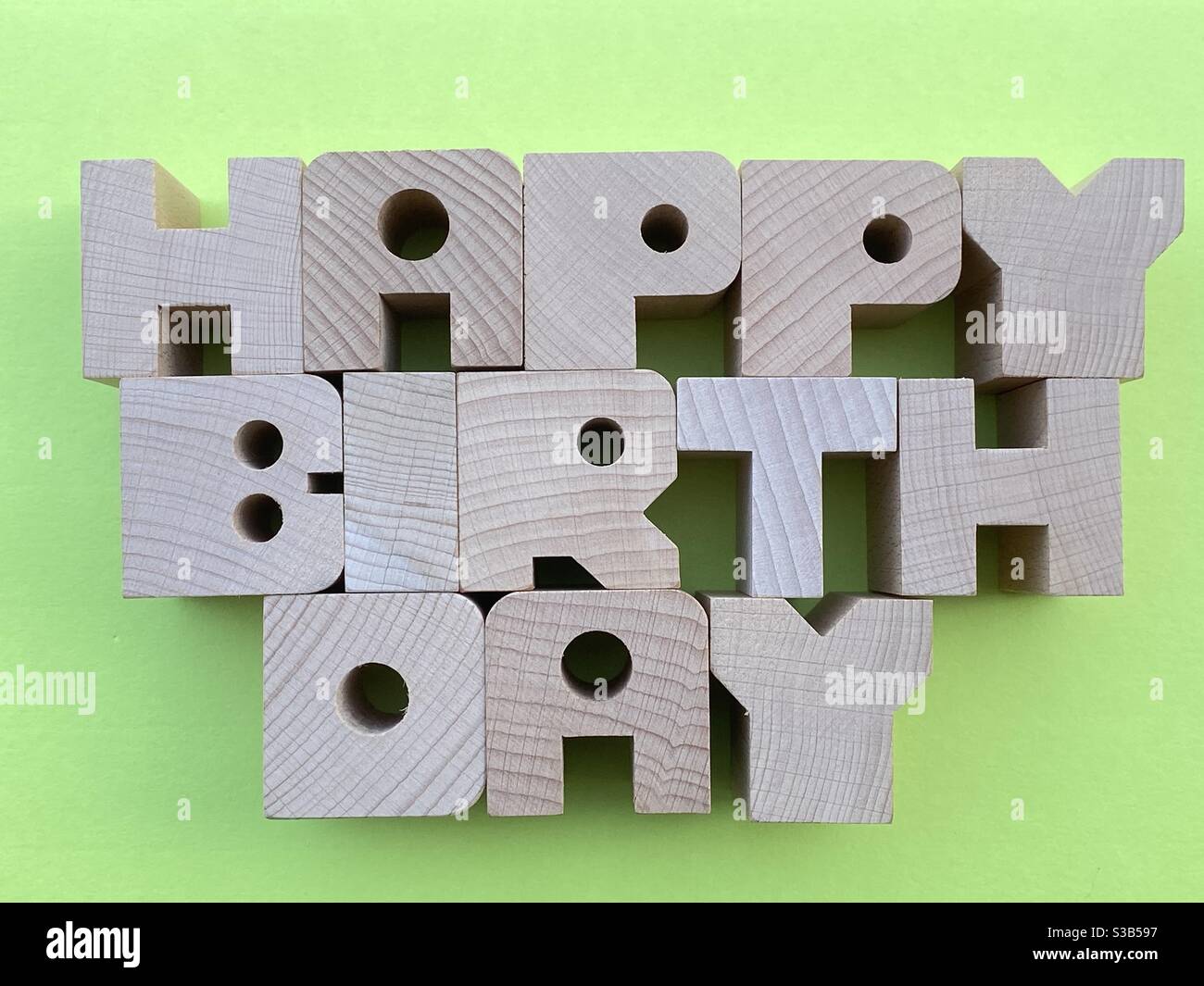 Happy Birthday Text mit Holzbuchstaben auf grünem Hintergrund komponiert Stockfoto