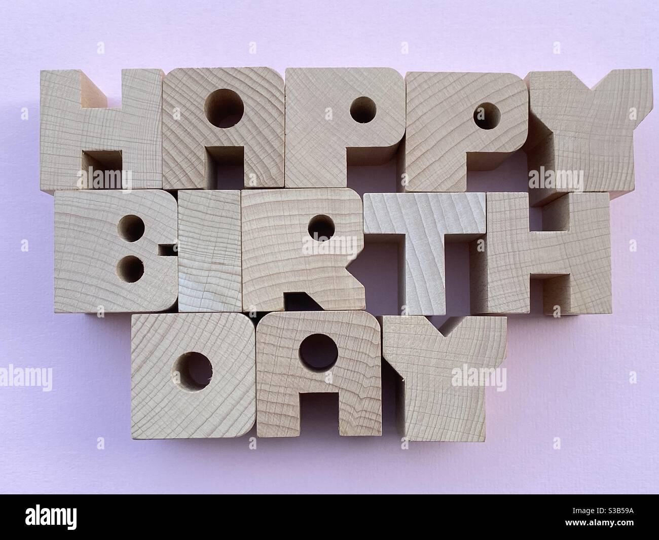 Happy Birthday Text mit Holzbuchstaben auf rosa Hintergrund komponiert Stockfoto