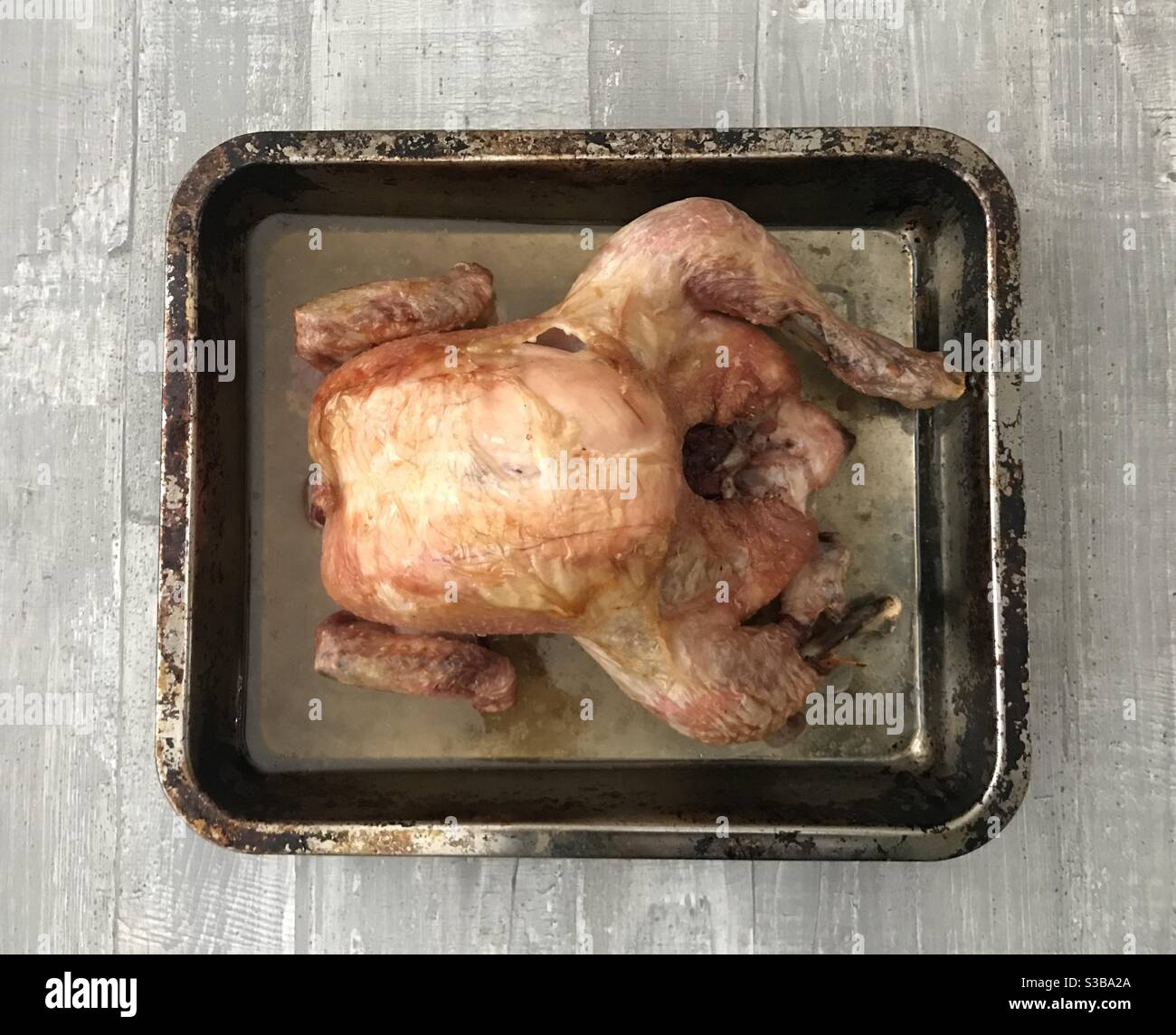 Frisch gebratenes Hähnchen auf einem Backblech auf Holz Hintergrund - Smartphone-aufgenommenes Stockfoto