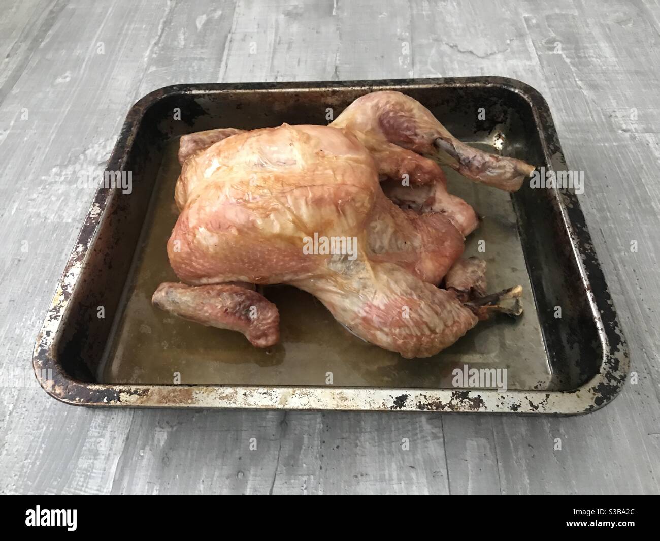 Frisch gebratenes Hähnchen auf einem Backblech auf Holz Hintergrund - Smartphone-aufgenommenes Stockfoto