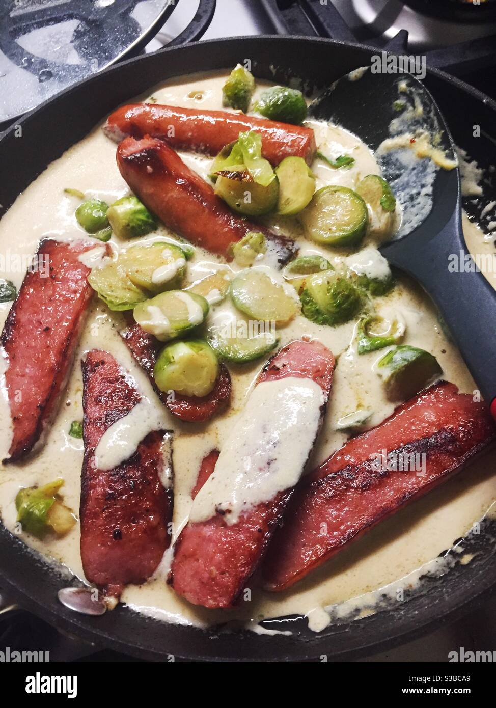 Nahaufnahme eines Gourmet-Vorspeisen aus rosenkohl und polnischer Wurst in einer cremigen Senfsauce. Stockfoto