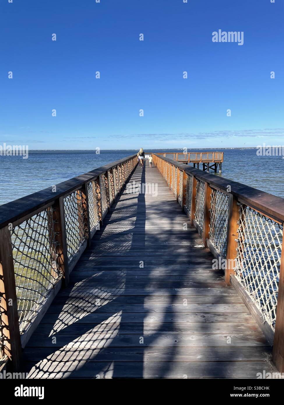 Junge Dame mit Kindern auf langen hölzernen Pier über dem Choctawhatchee Bay Florida Stockfoto