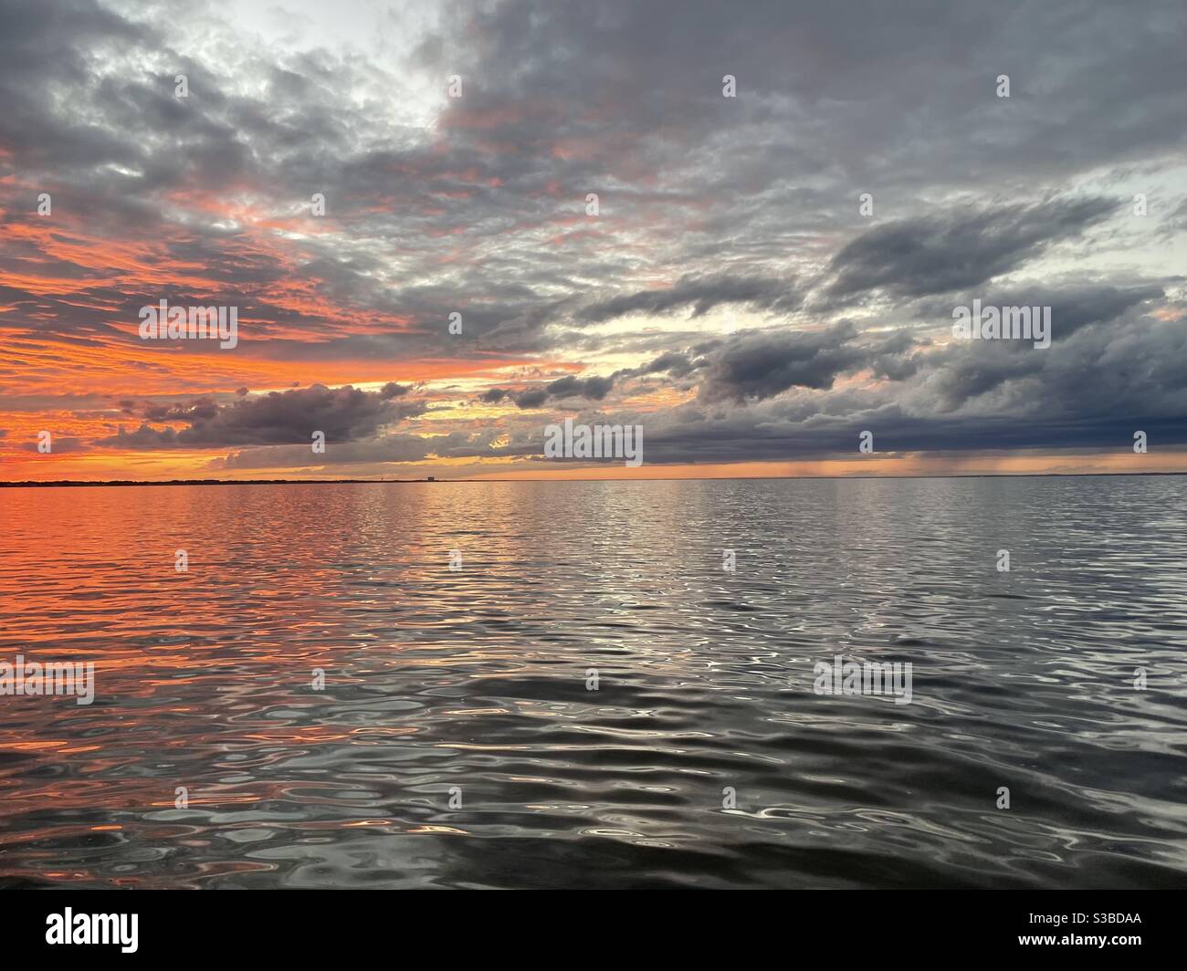 Der Himmel bei spätem Sonnenuntergang mit Wolken und Reflexionen auf der Bucht Wasser Stockfoto