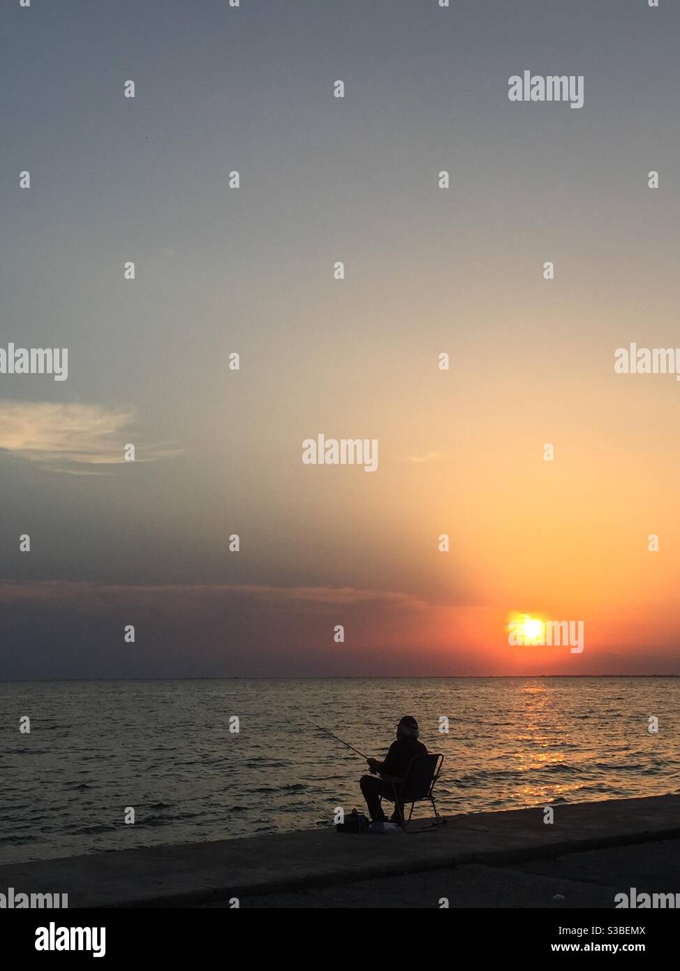 Mann, der während der Sonnenuntergangszeit in thessaloniki angeln kann. Stockfoto