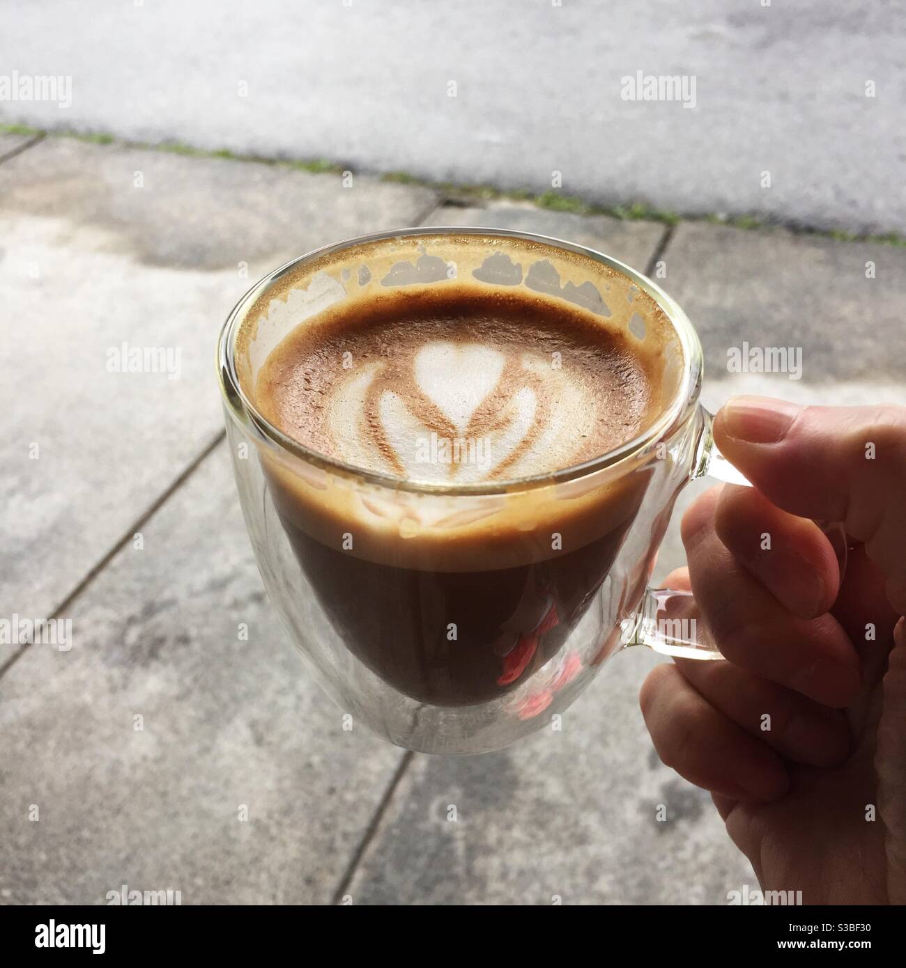 Frau hält eine Tasse Latte - Smartphone-aufgenommenes Stockfoto