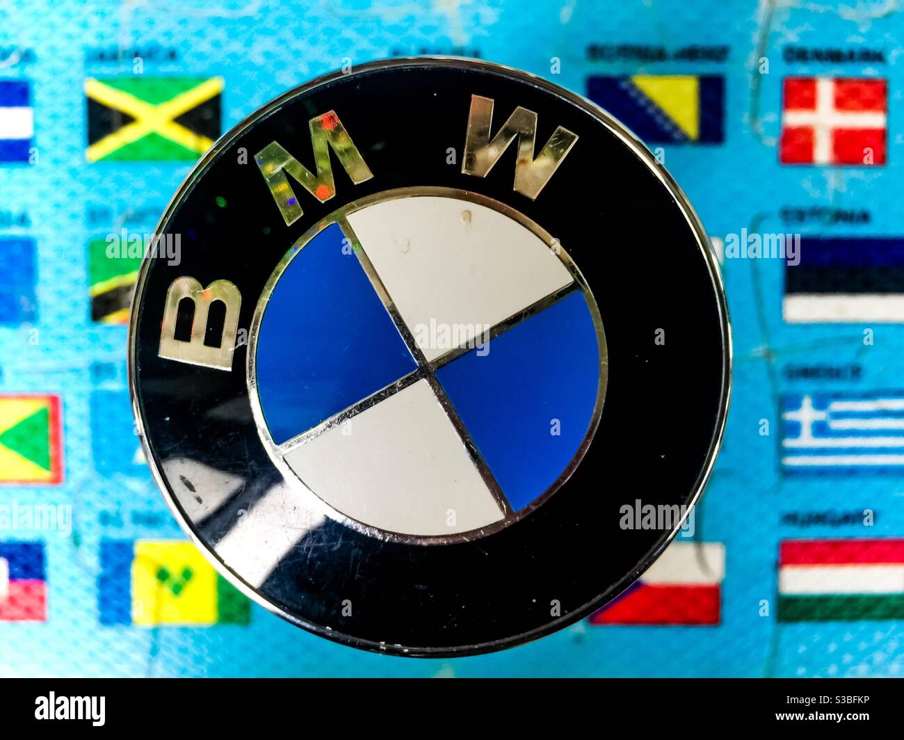 BMW sticht in der Welt des Motorsports hervor, symbolisiert durch sein Logo vor dem Hintergrund von Länderflaggen. Konzeptuelles Image. Kultig. Symbolisch. Stockfoto