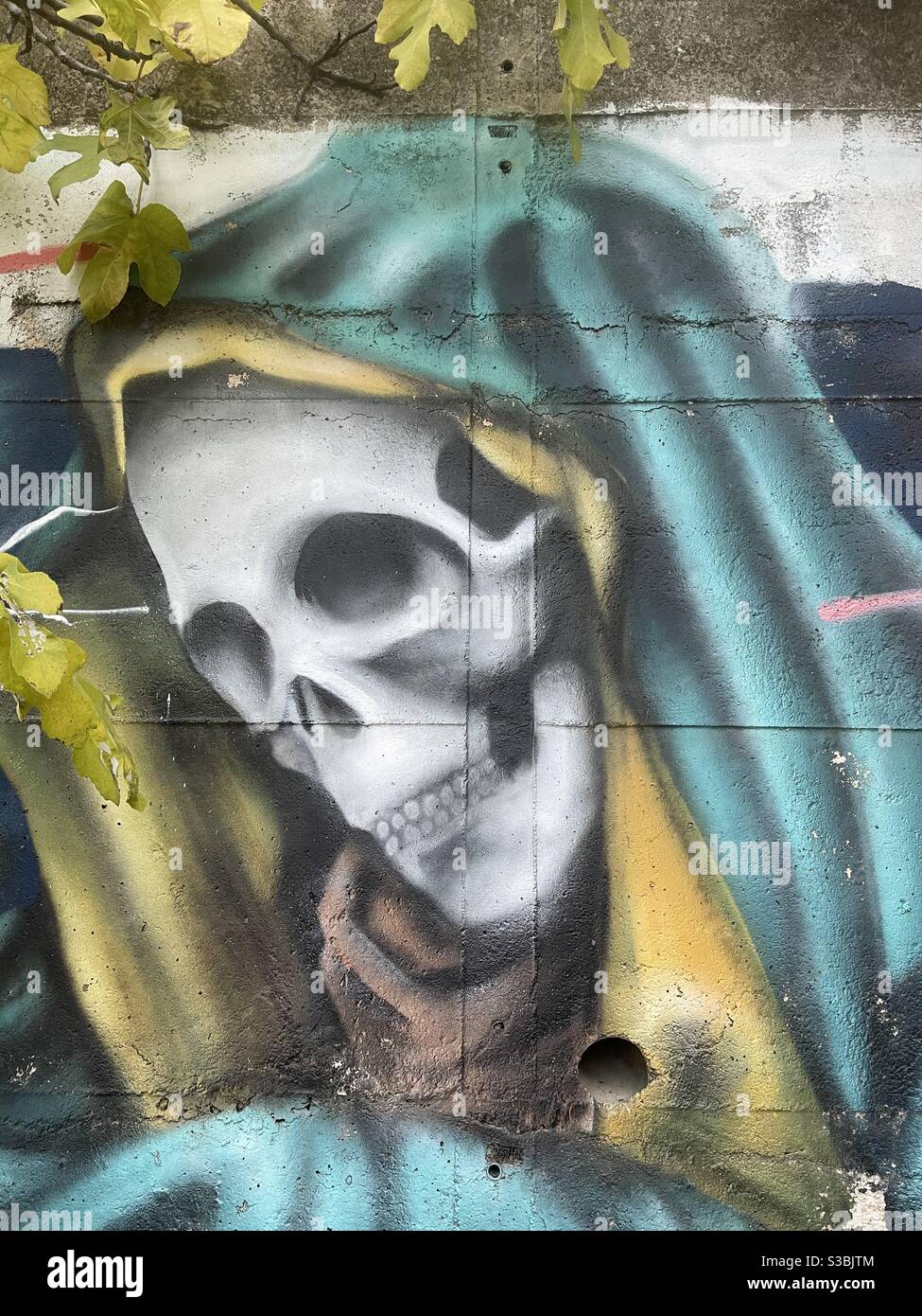 Gekleideter Tod, konzeptuelles Airbrush-Design an einer Stadtmauer - Smartphone-aufgenommenes Stockfoto