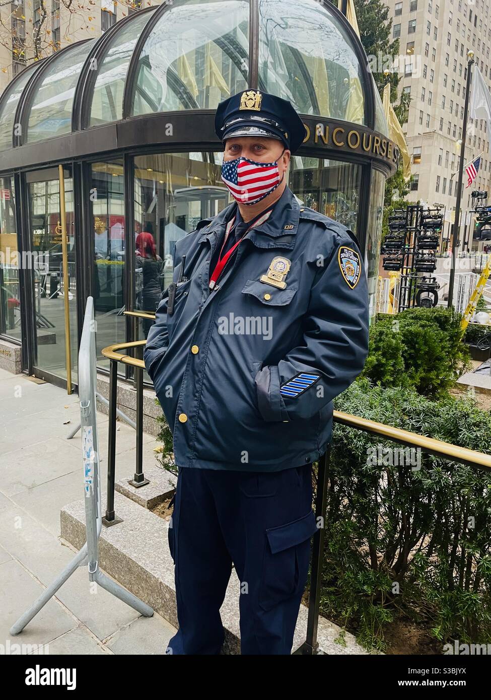 New York City Polizist am Rockefeller Center vor dem Beleuchtung des Weihnachtstrers - Smartphone-aufgenommenes Stockfoto