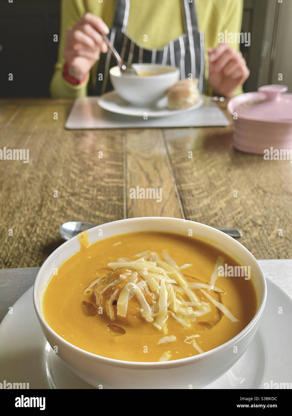 Schüssel Suppe mit Frau im Hintergrund essen - Smartphone-aufgenommenes Stockfoto