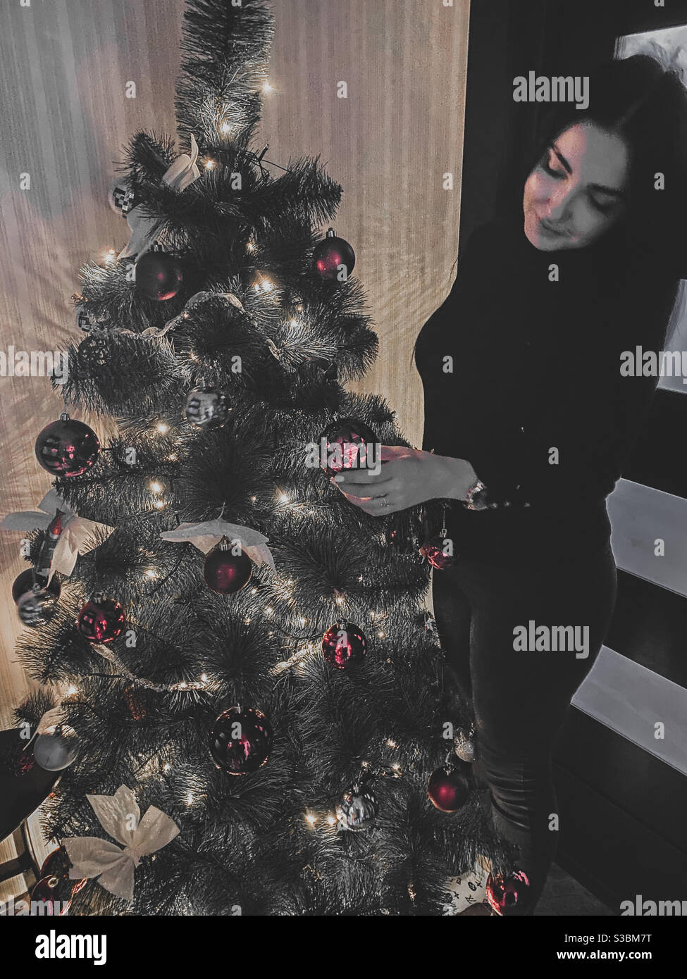 Eine junge Dame, die 2020 einen Weihnachtsbaum schmückt Stockfoto