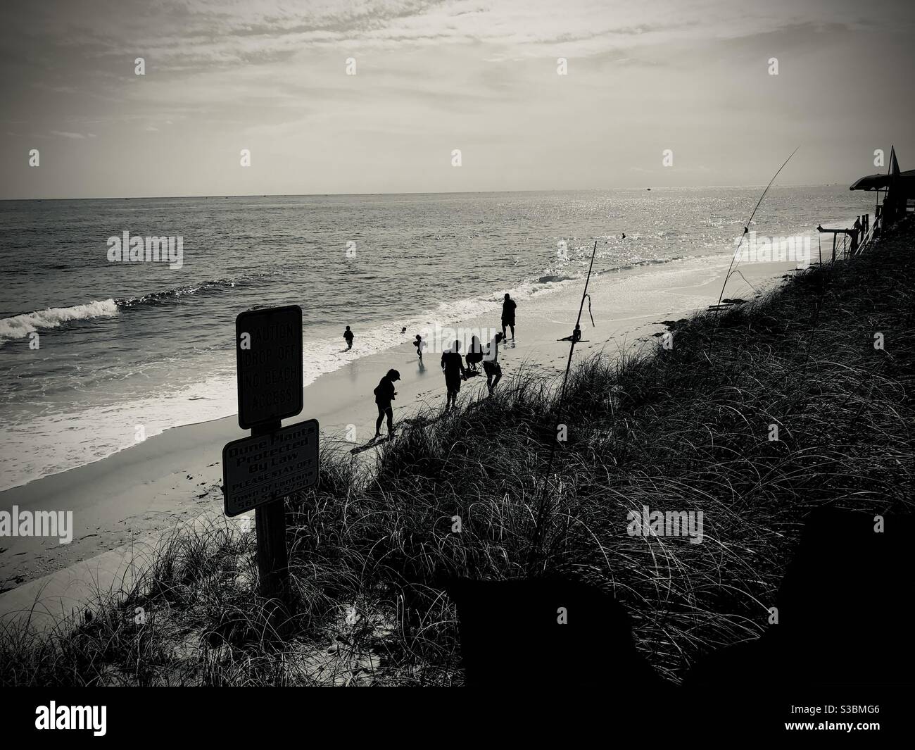 Dramatische Szene in Schwarz und Weiß von Menschen, die am Strand und am Meer entlang gehen, Lantana, Florida. - Smartphone-aufgenommenes Stockfoto