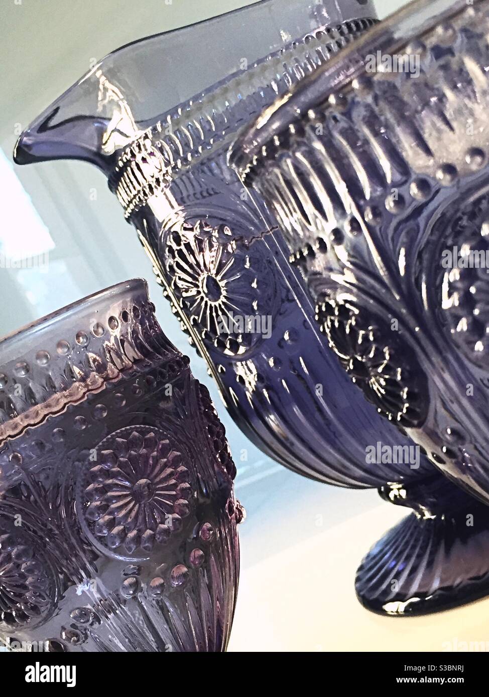 Nahaufnahme von geätzten purpurnen Glasgefäßen und Becher. Stockfoto