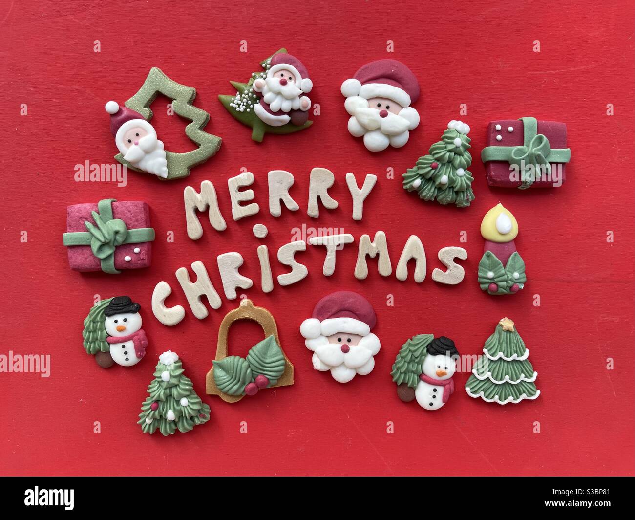 Frohe Weihnachten mit Holzbuchstaben und Marzipan Weihnachten Symbole über Roter Hintergrund Stockfoto
