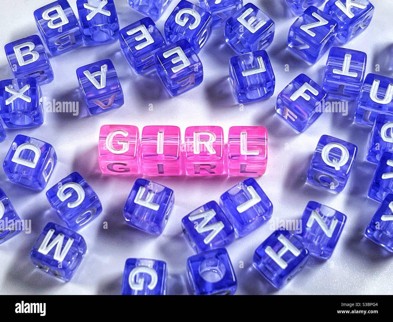 Kleine Blöcke Schreibweise "Mädchen" in rosa mit zufälligen Buchstaben in blau. Gender Reveal Konzept. Stockfoto