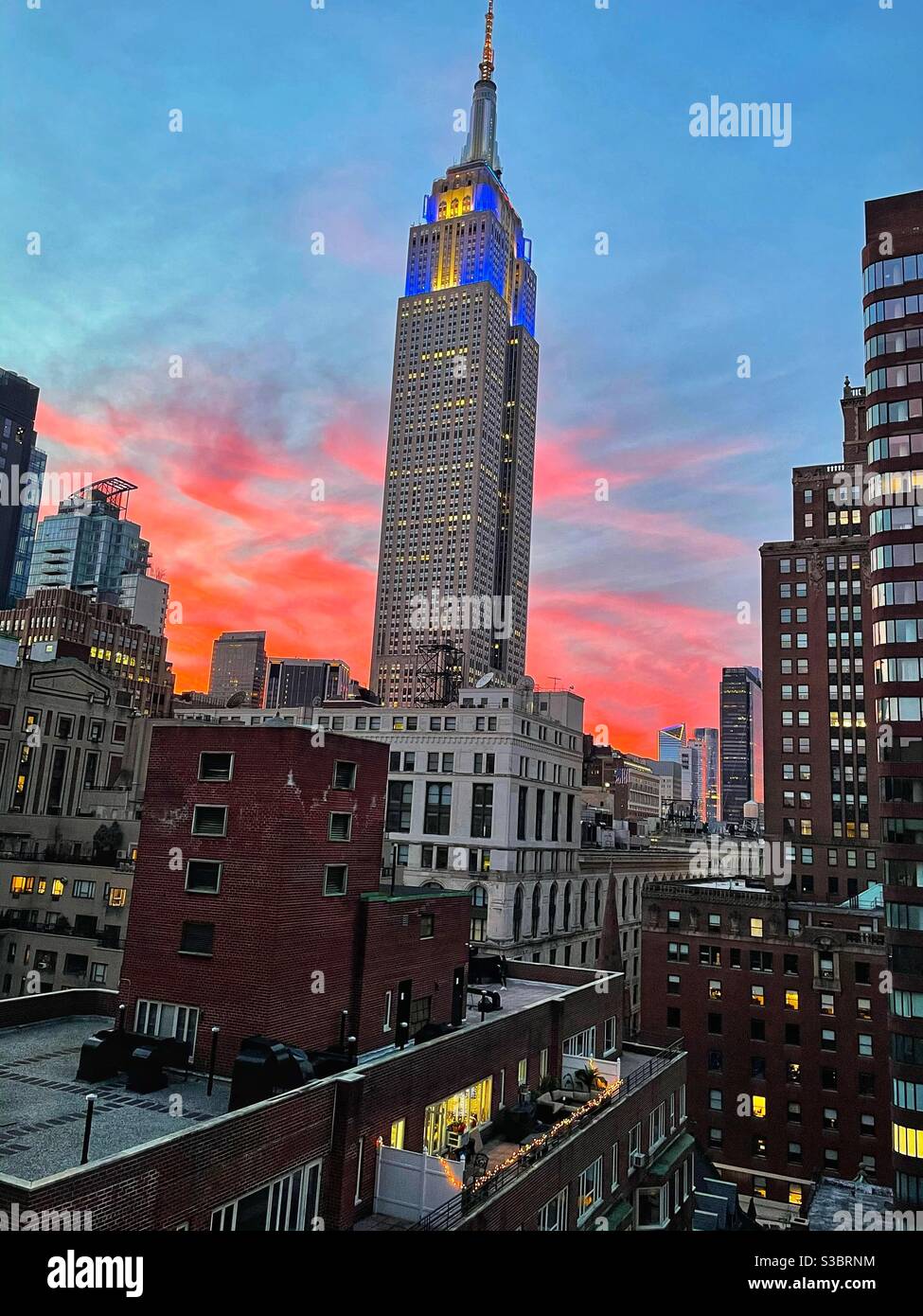 Channukah leuchtet im rosigen Schein der Dämmerung auf dem Empire State Building. Kein Ort wie New York für die Feiertage! - Smartphone-aufgenommenes Stockfoto