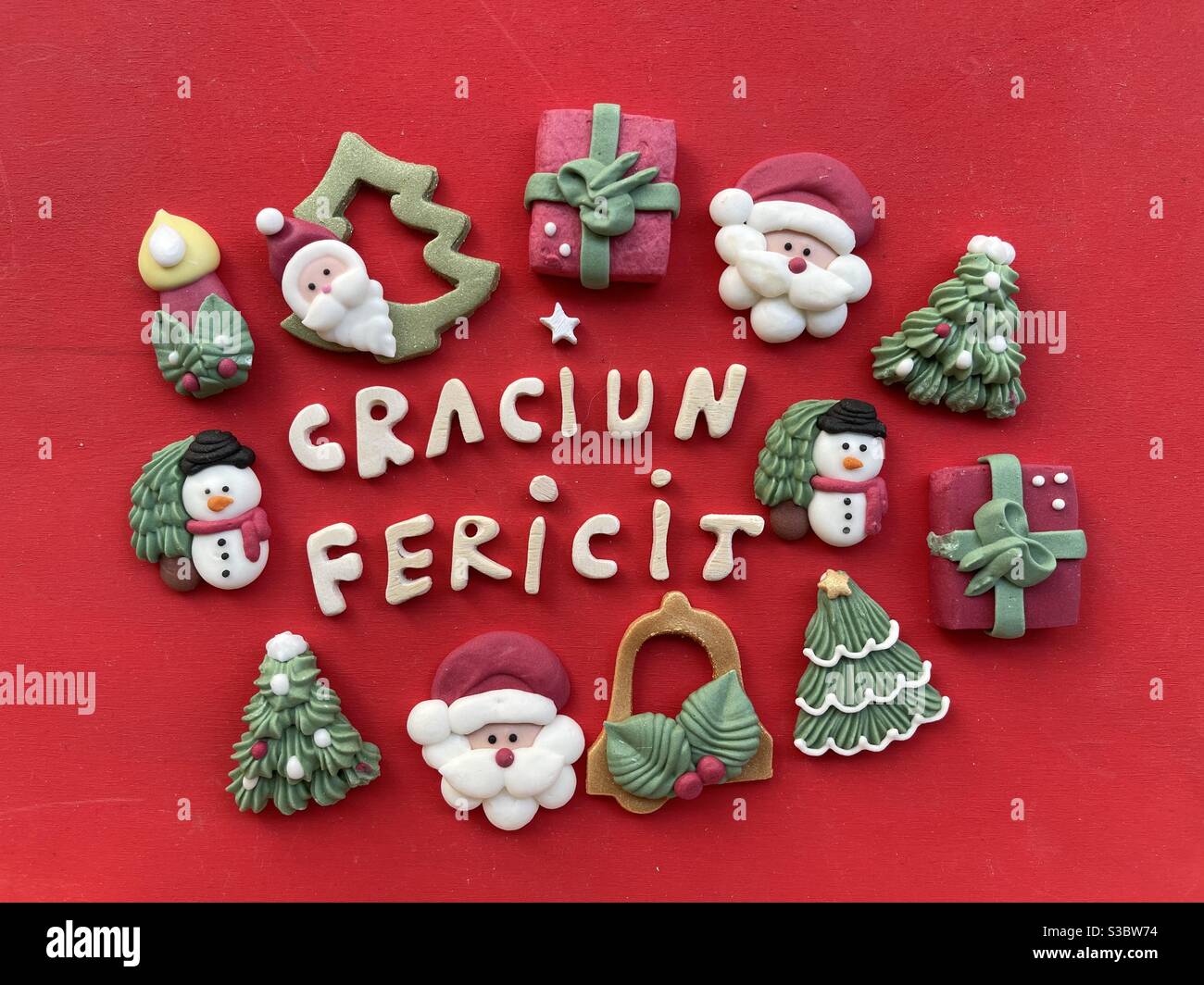 Craciun Fericit, heiraten Weihnachten in rumänischer Sprache mit Holzbuchstaben und Marzipan Weihnachten Symbole auf rotem Hintergrund Stockfoto