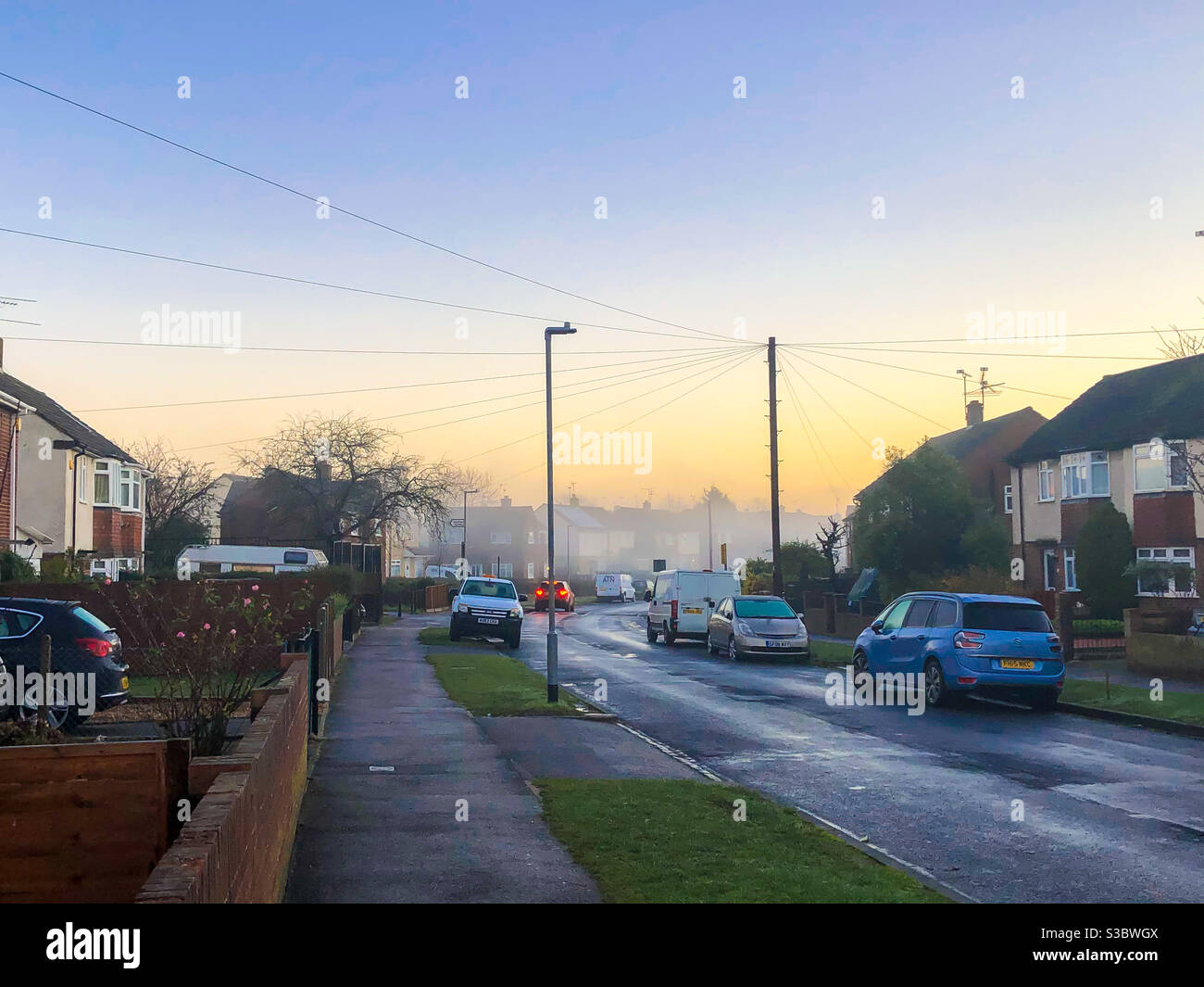 Ein nebliger Start in den Tag mit Blick nach Osten eine Wohnstraße in Reading, Großbritannien, mit einem gelben Schein am Himmel. - Smartphone-aufgenommenes Stockfoto