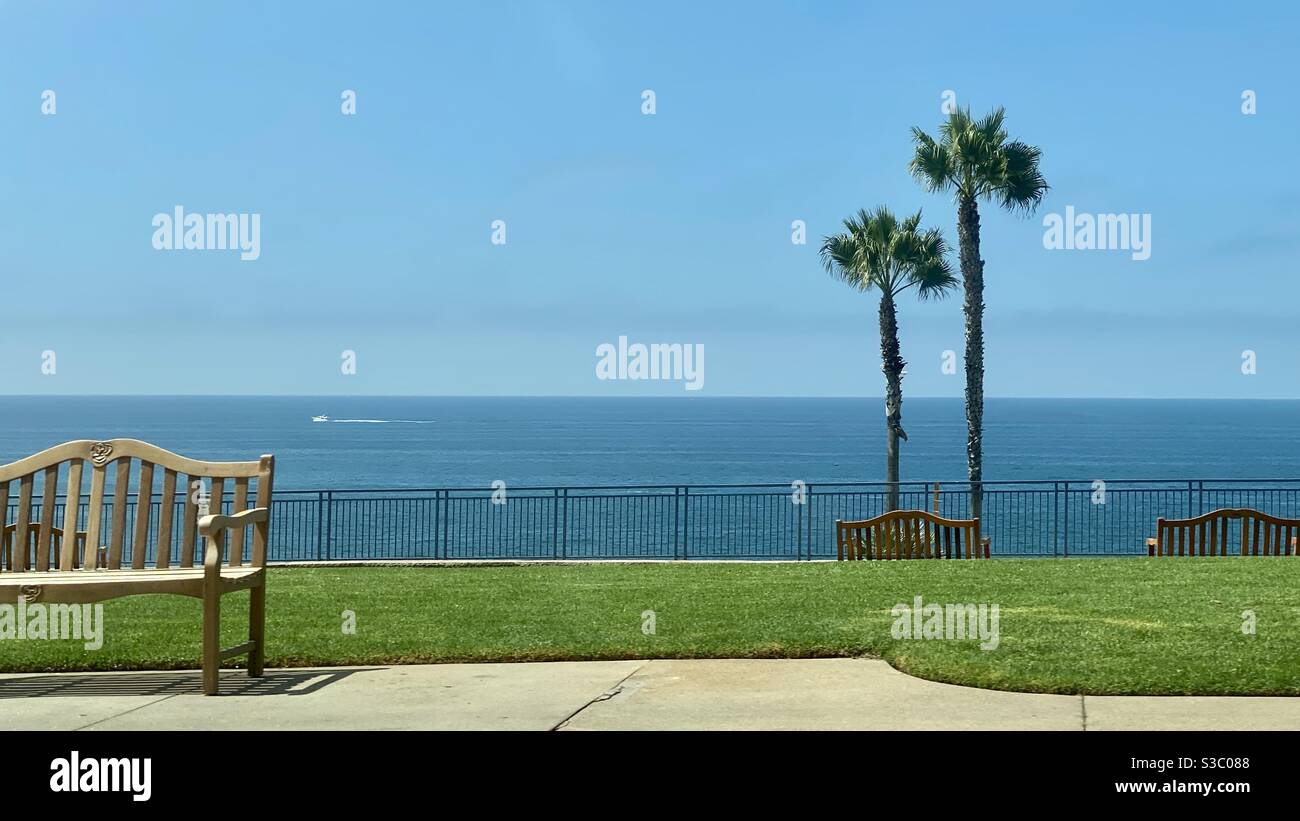 Pazifischer Ozean mit Palmen, Stühlen und Geländern an einem Hang mit Blick auf das Meer am Laguna Beach in Kalifornien, USA - Smartphone-aufgenommenes Stockfoto