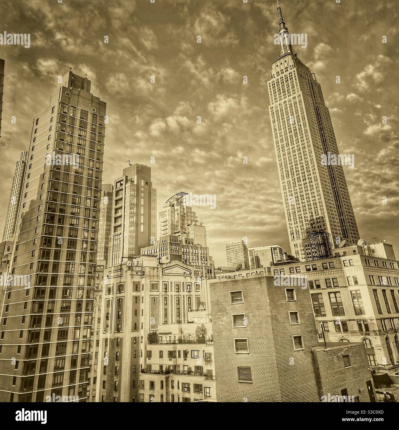 Sepiafarbene Ansicht der Wolkenkratzer von Manhattan, einschließlich des Empire State Building von der Park Avenue, Murray Hill, in Richtung Südwesten, Midtown, mit flauschigen Wolken im Hintergrund. - Smartphone-aufgenommenes Stockfoto
