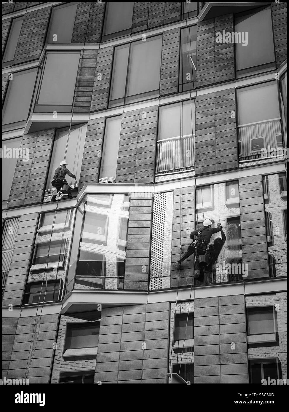 Schwarz-Weiß-Foto von Fensterputzern, die an einem Gebäude im Silo-Viertel der V&A Waterfront, Kapstadt, Südafrika arbeiten. Stockfoto