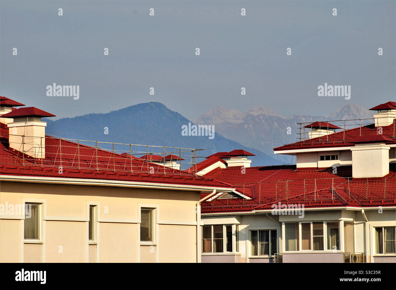 Dächer von Häusern im Sonnenlicht vor dem Hintergrund von Bergen Stockfoto